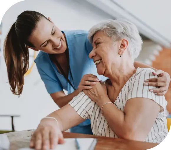 A caregiver warmly supporting an elderly woman.