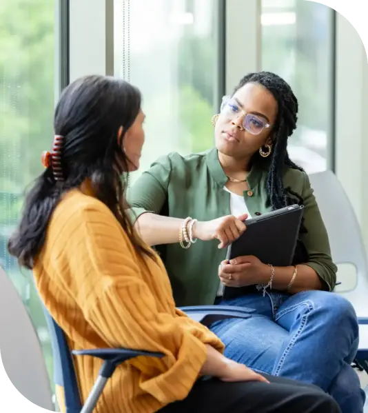 A counselor attentively listens to a woman during a therapy session.